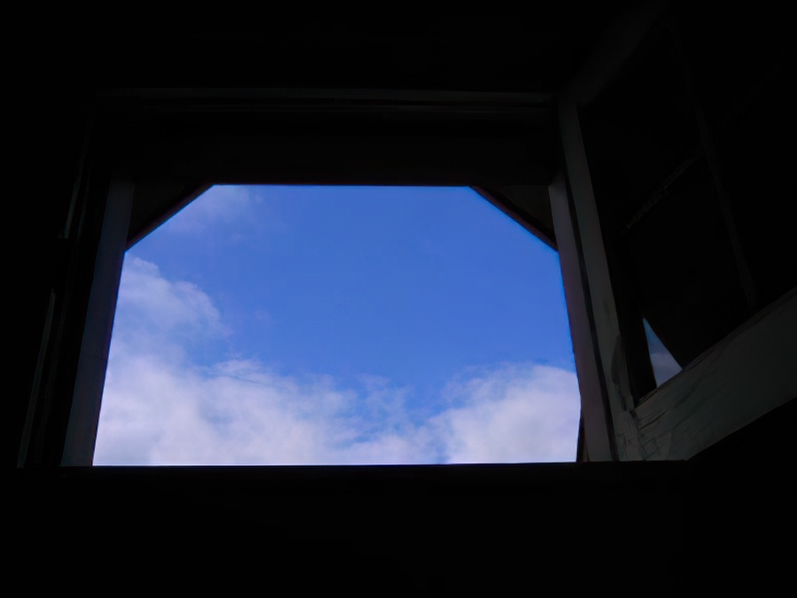 Looking out the window into a blue sky with clouds.