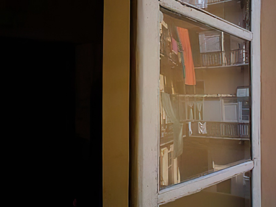 Reflection of clothes on a balcony in an open window.