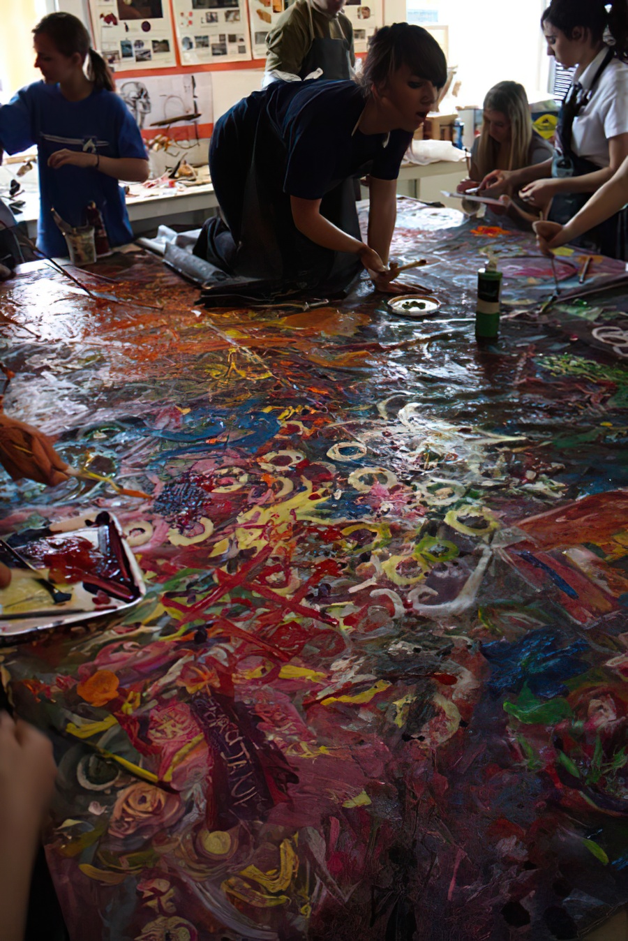 A student on the table painting on a large unstretched canvas.