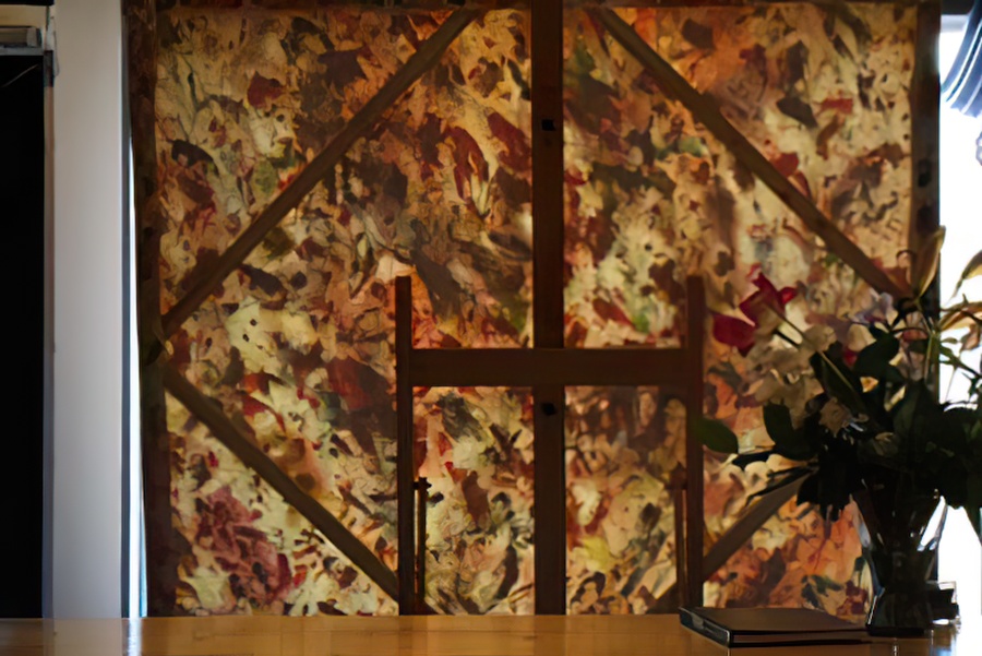 A photo of a painting on the easel, from behind, in the window.